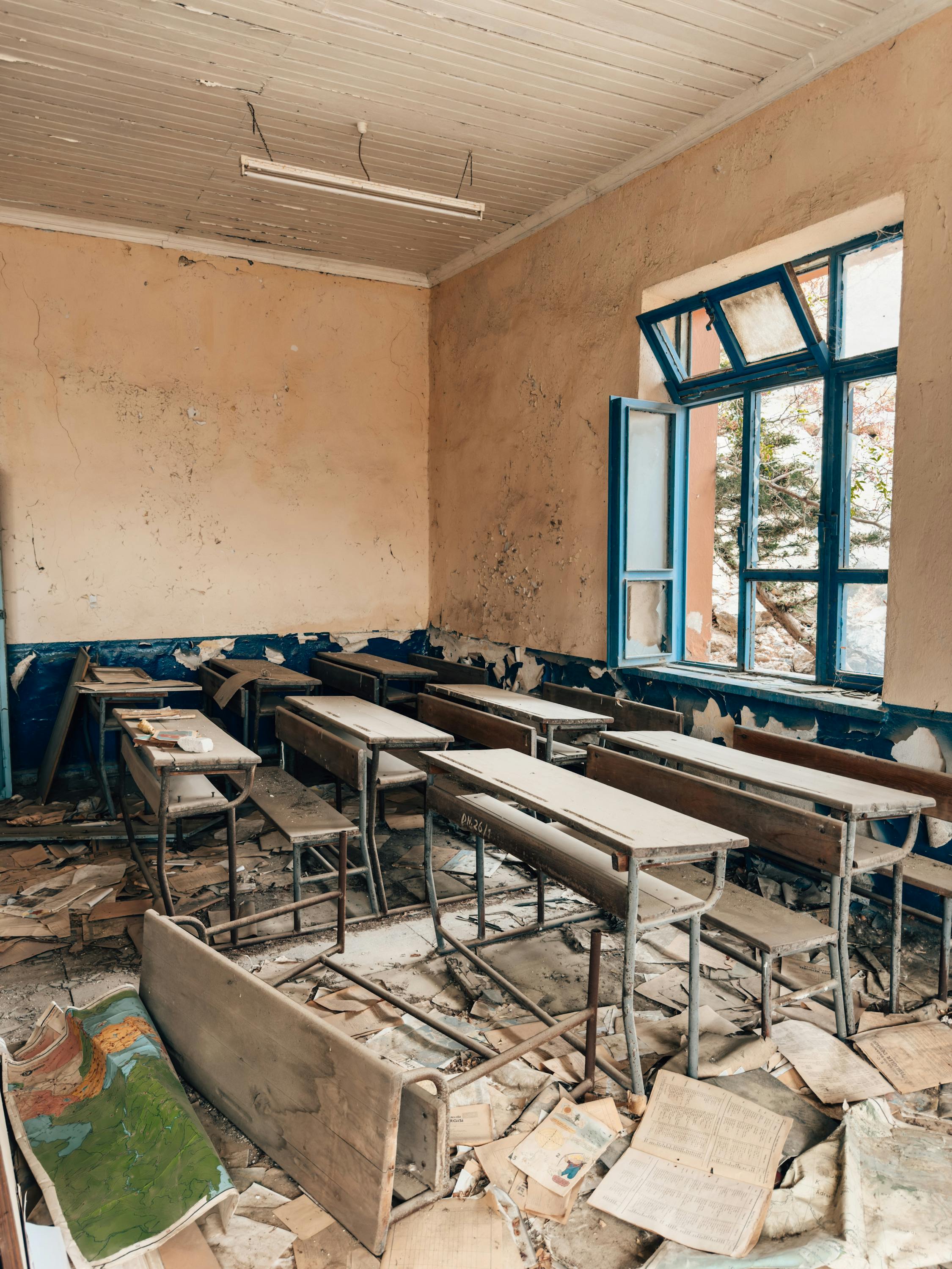 abandoned classroom with broken desks and peeling walls