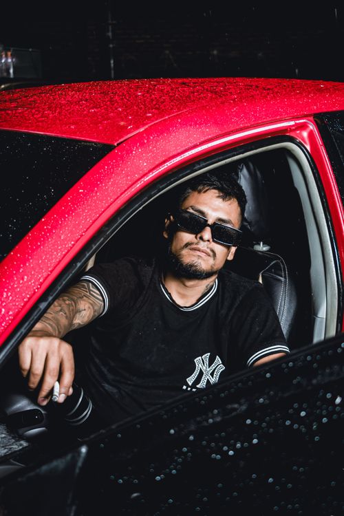 Free Man in a black t-shirt with sunglasses sitting in a red car at night. Stock Photo