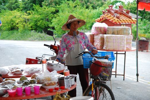 An elderly vendor with a bicycle at an outdoor food market, showcasing local goods.