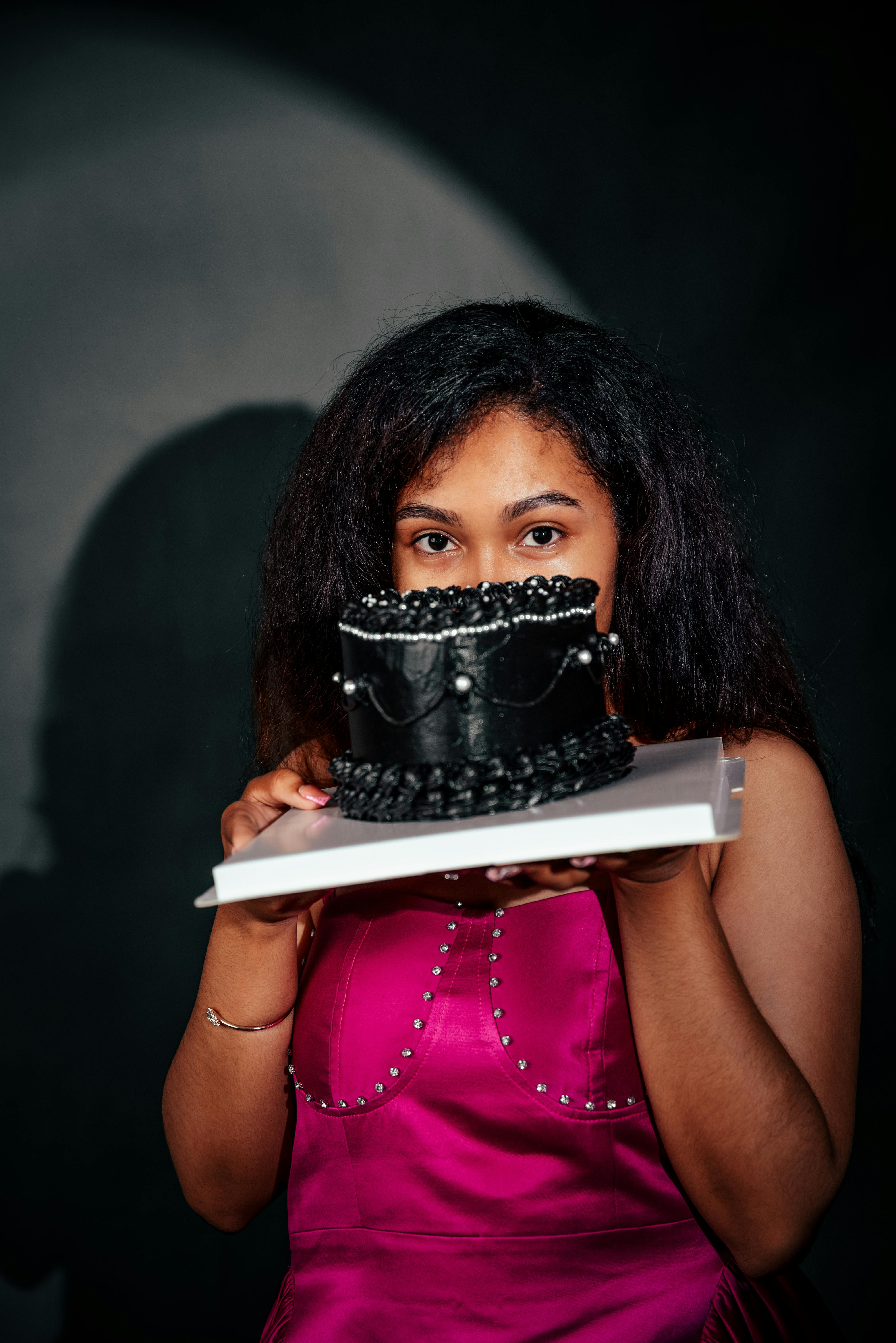 young woman with chic black cake in studio