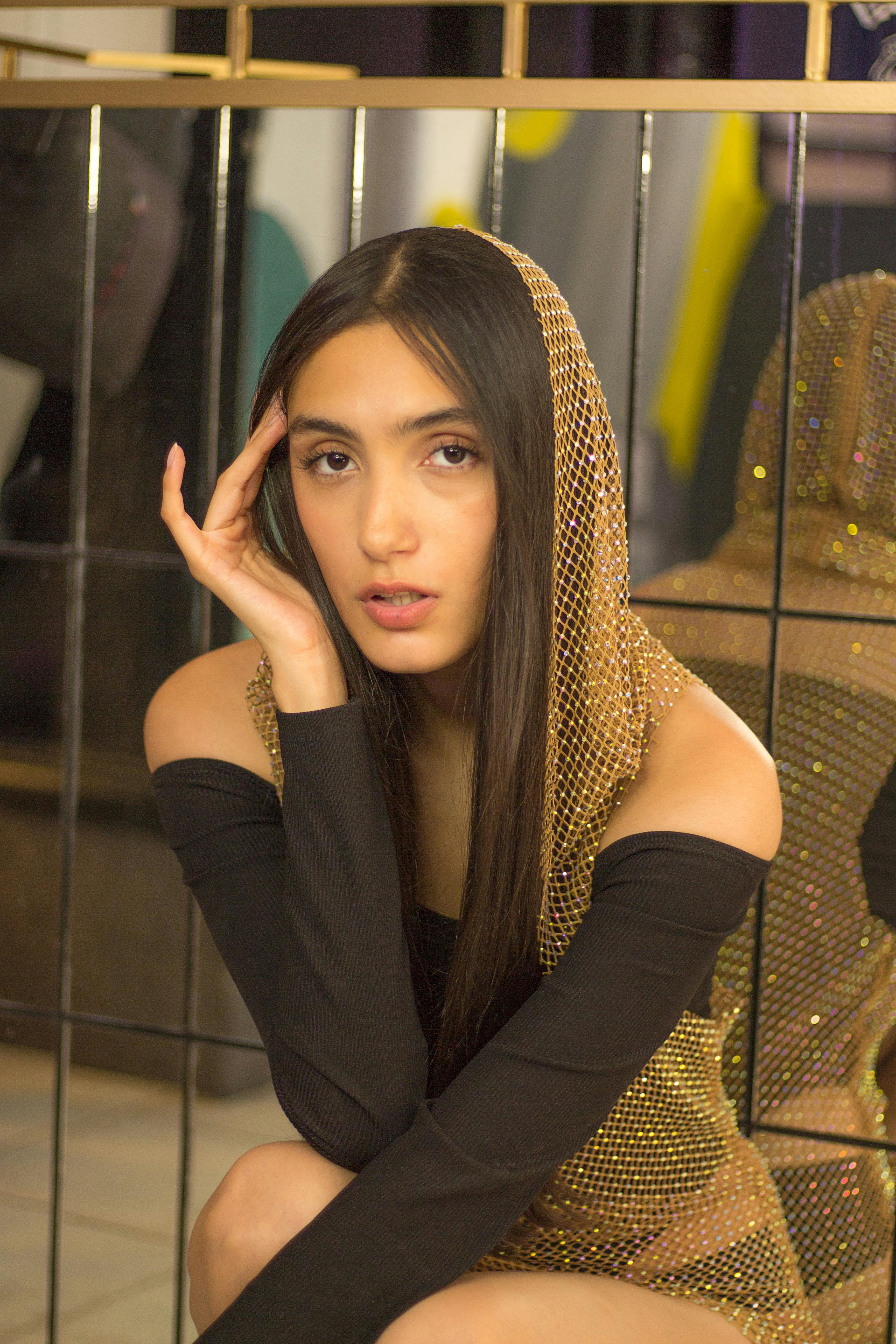 Free Portrait of a young woman in a stylish outfit with a reflective backdrop, exuding elegance and mystery. Stock Photo