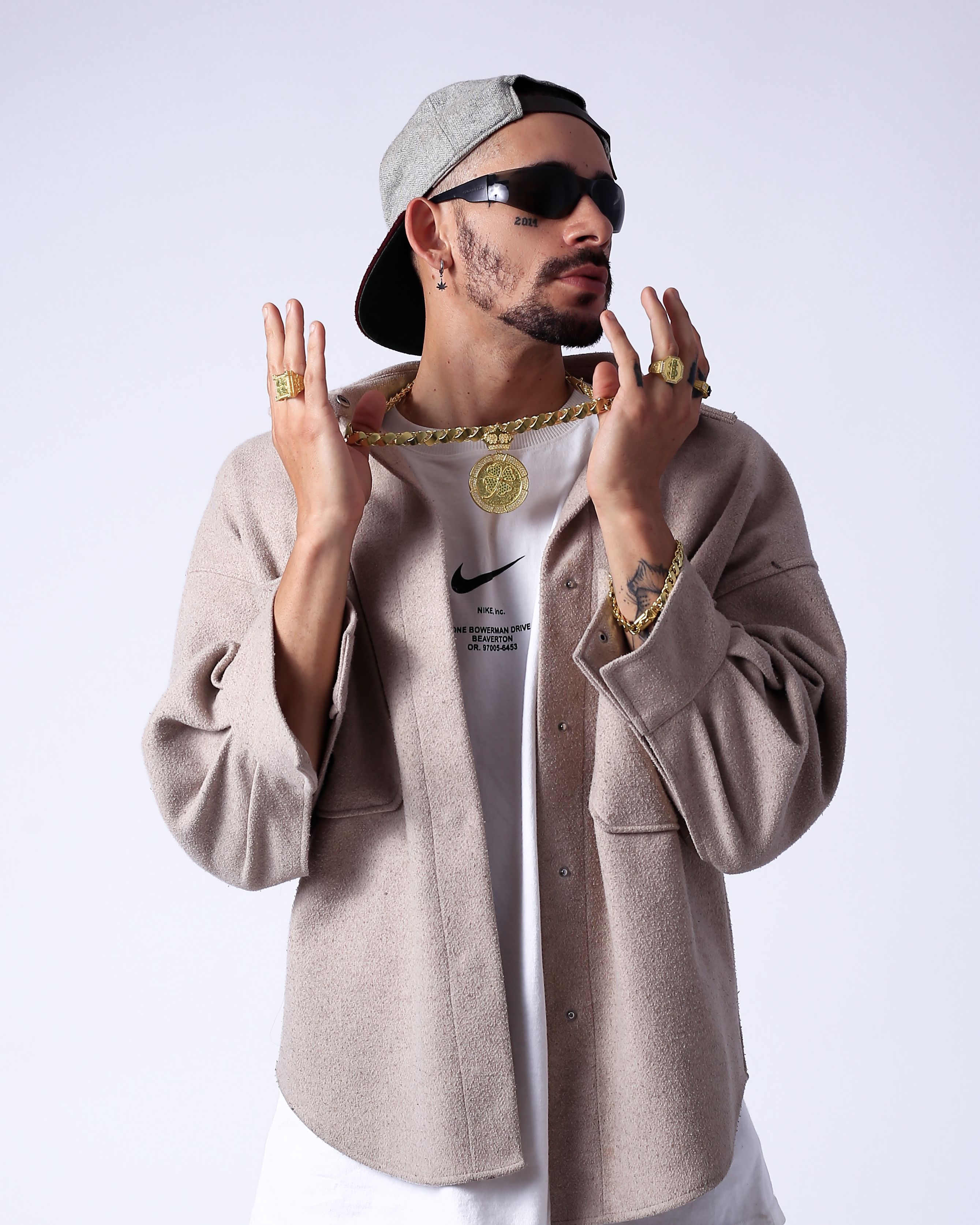 A fashionable young man exudes style in a chic urban outfit with gold accessories.