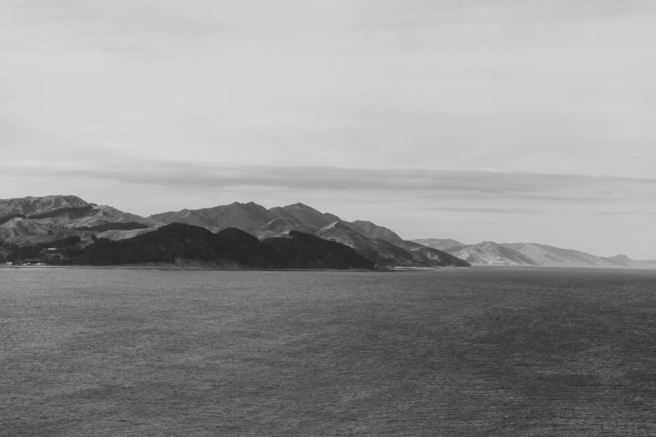 Black and white coastal view of the North Island, New Zealand, showcasing mountains and ocean.