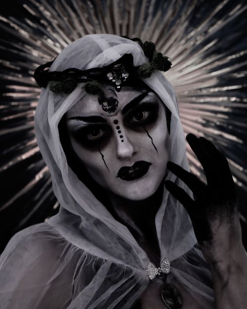 Free Expressive gothic cosplay portrait of a person with dramatic makeup and veil, set against a radiant background. Stock Photo