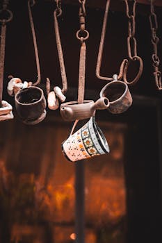 Rustic ceramic mugs with floral patterns hang on metal hooks, evoking vintage charm.
