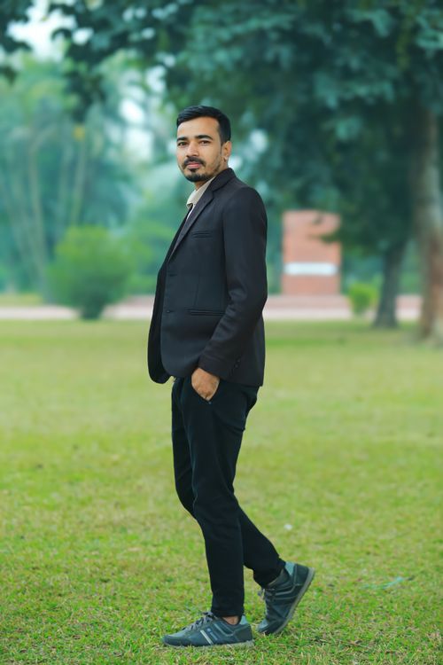 Free Man in a suit standing confidently outdoors in a park setting. Stock Photo