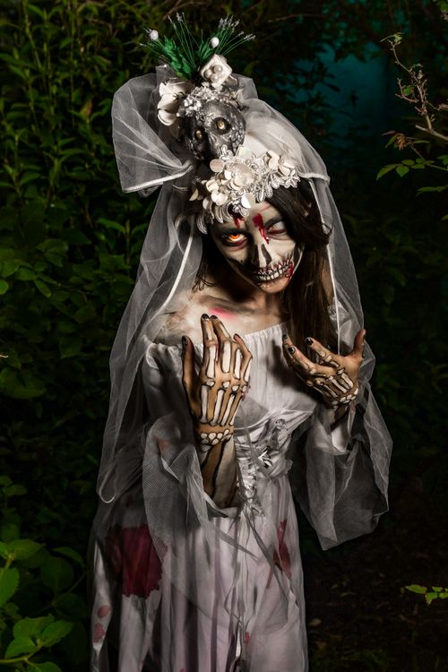 Free Eerie bride in skeleton makeup and costume in a dark forest setting. Stock Photo