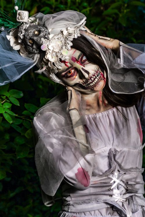 Free Haunting portrait of a woman in a zombie bride costume with intense makeup and eerie expression. Stock Photo