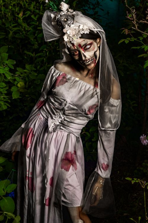 Free Eerie zombie bride with skeleton makeup and vintage dress in a nighttime forest. Stock Photo