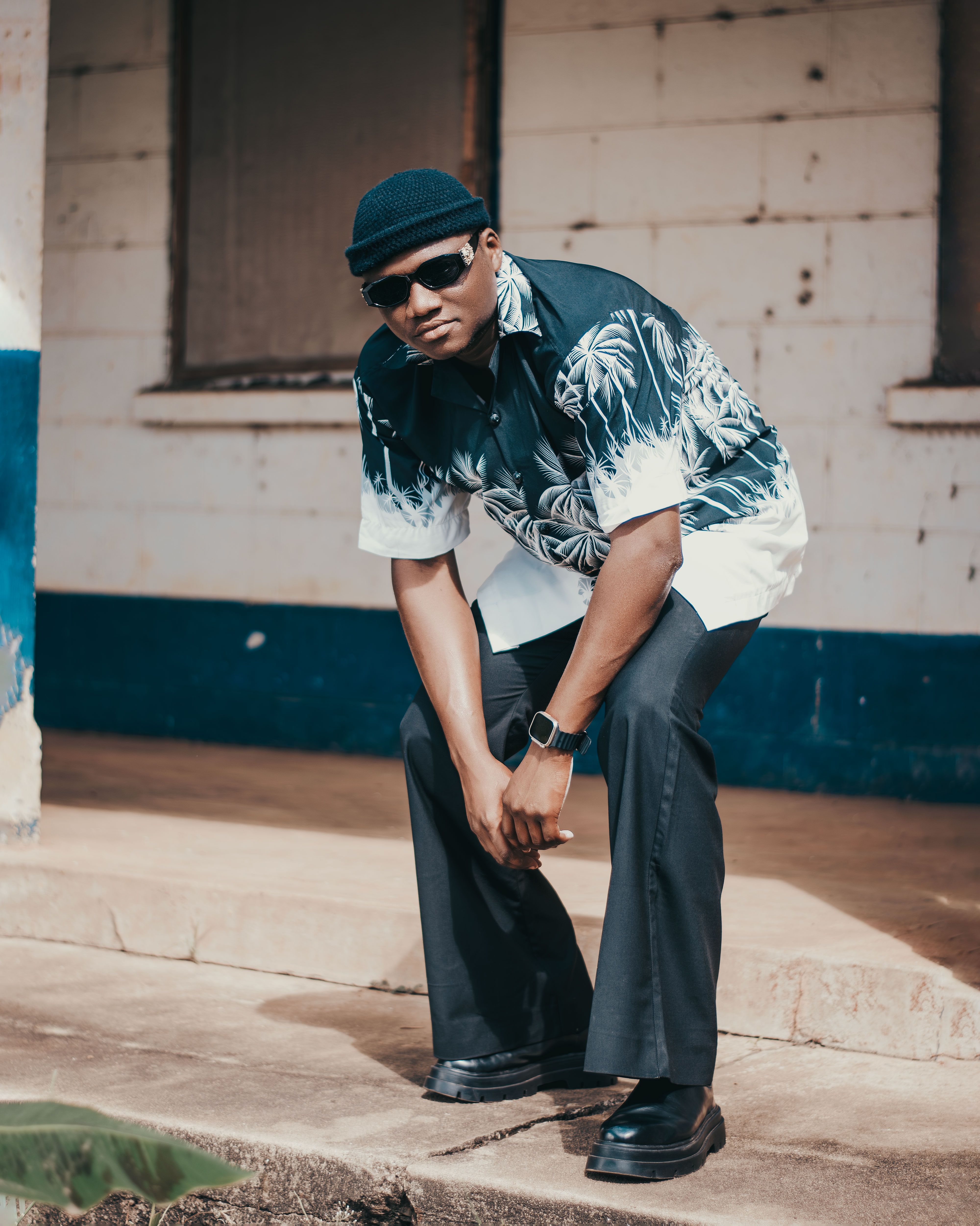 A man in casual attire poses confidently outdoors with cool demeanor.