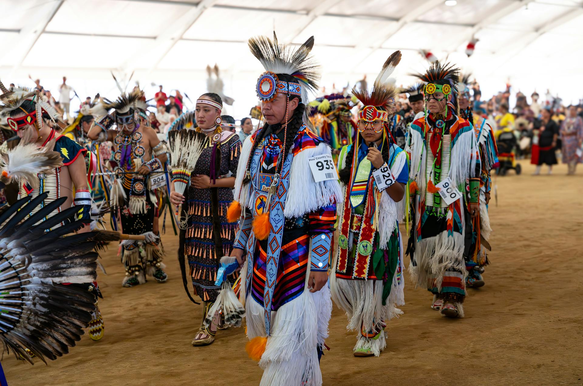 Native American dancers in colorful traditional attire at a vibrant pow wow gathering.