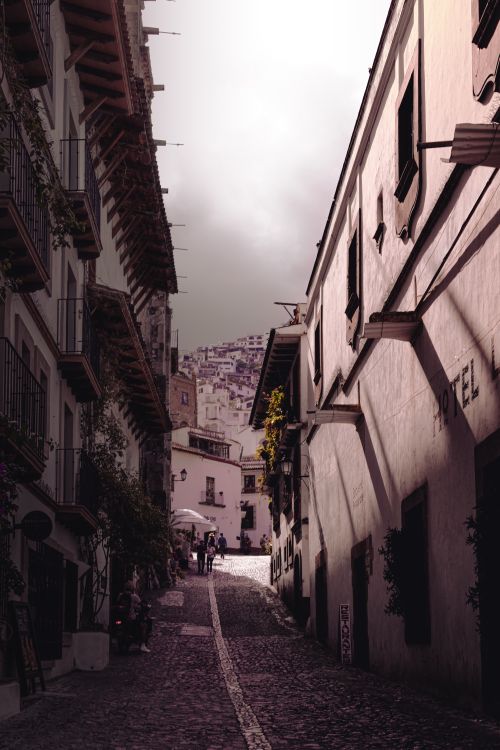 Free Picturesque narrow cobblestone street in a European old town at twilight, with classic architecture and shadows. Stock Photo