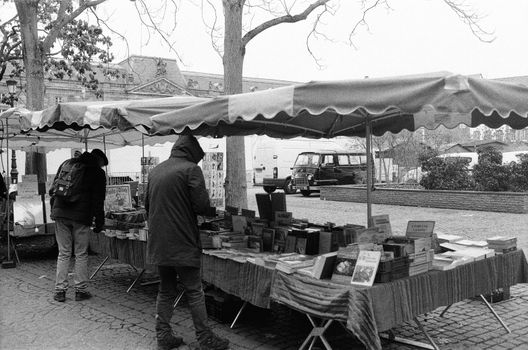 Black and white photo of an outdoor book market with people browsing.