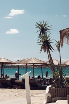 Chic beach in Naxos, Greece, with sun loungers and umbrellas under a clear summer sky.