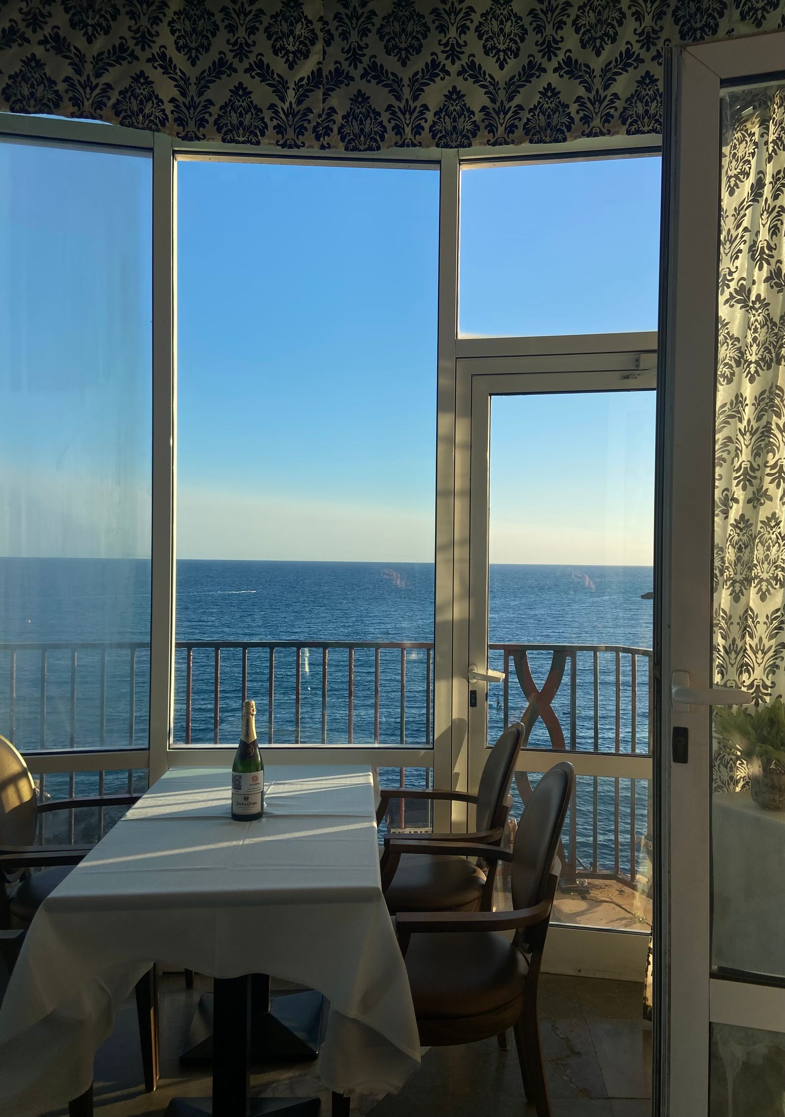 Warm dining room facing the water at sunset with tables set for dinner.