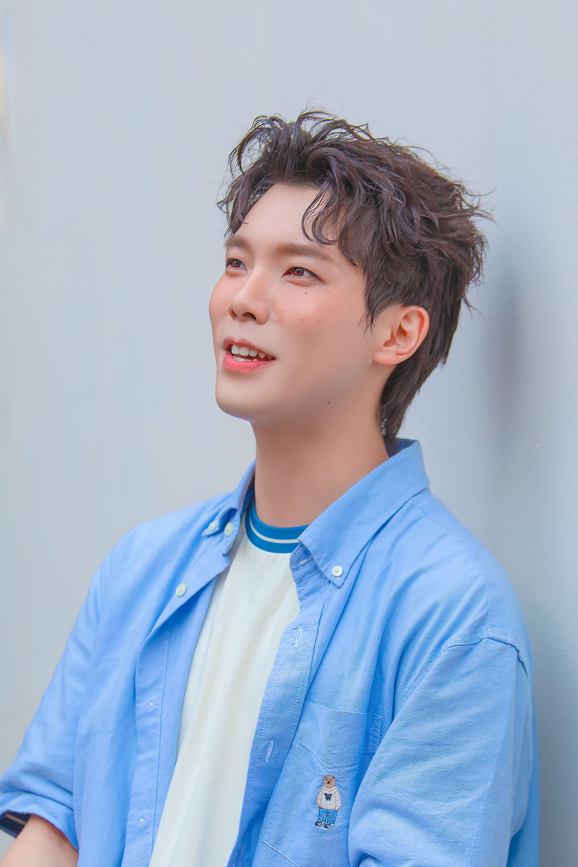 Asian male with casual hairstyle smiling against a plain background.