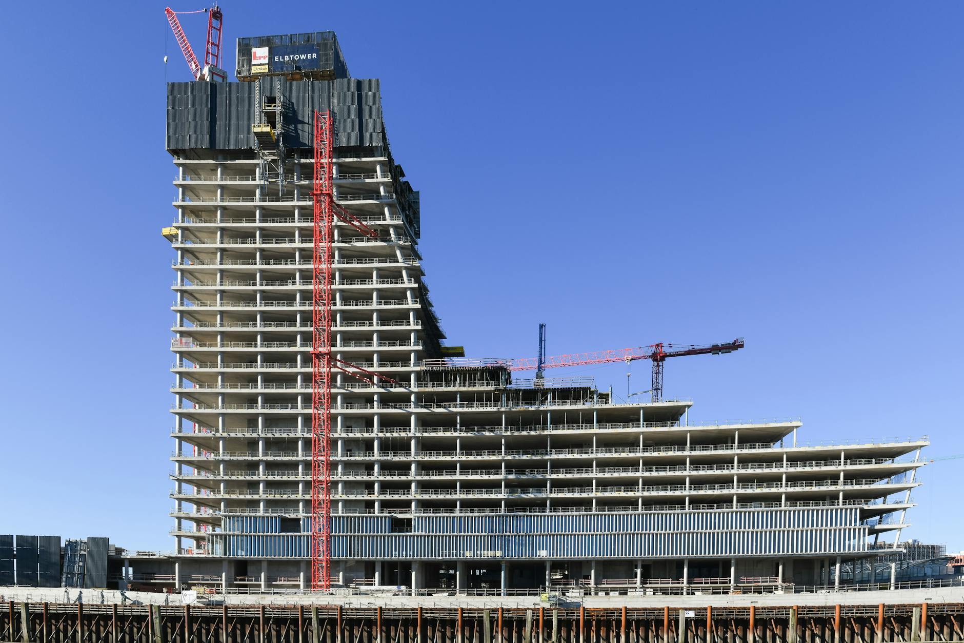 Aerial view of a modern high-rise under construction in Hamburg, featuring cranes and concrete structures.