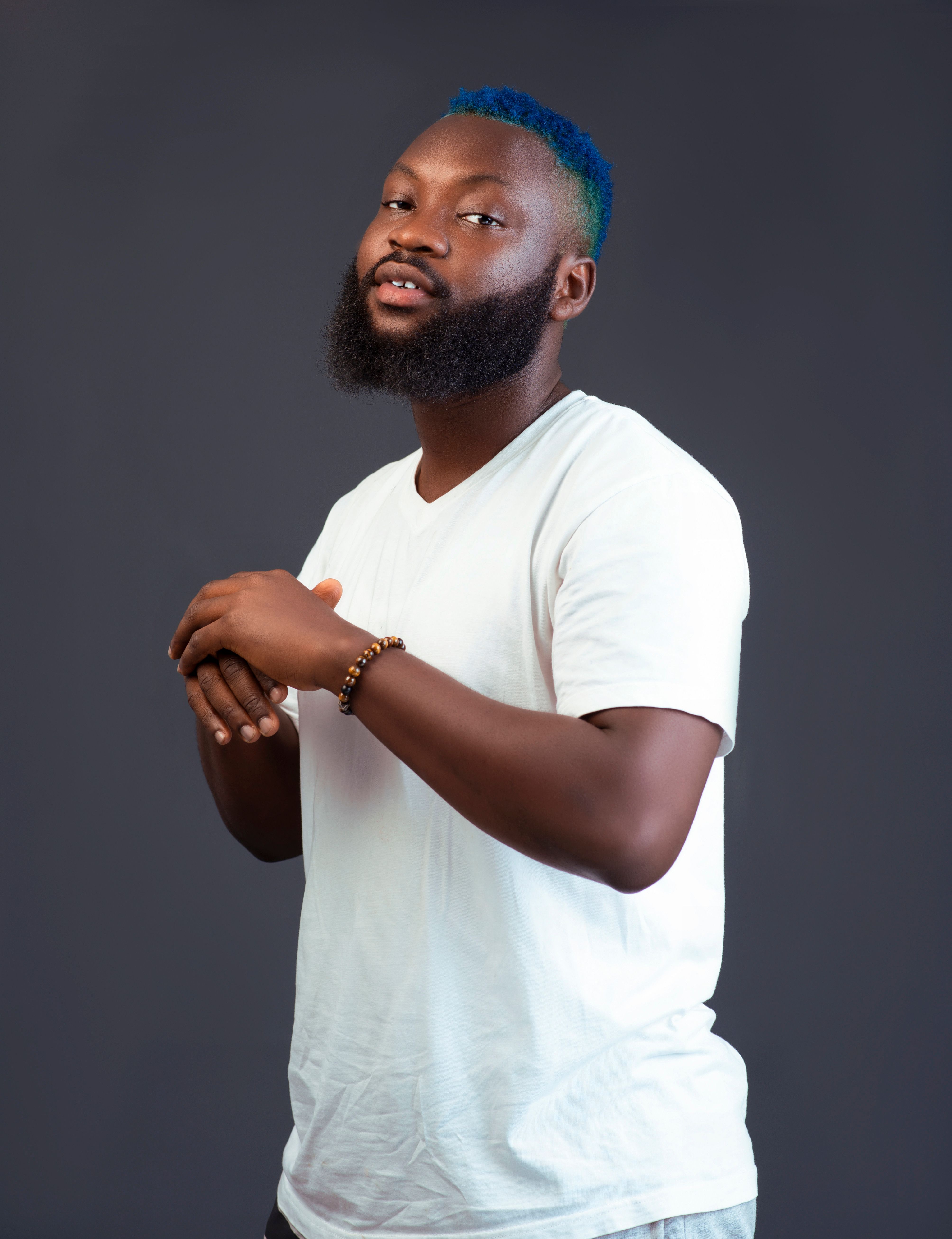 Portrait of a confident man with a blue hairstyle and beard wearing white.