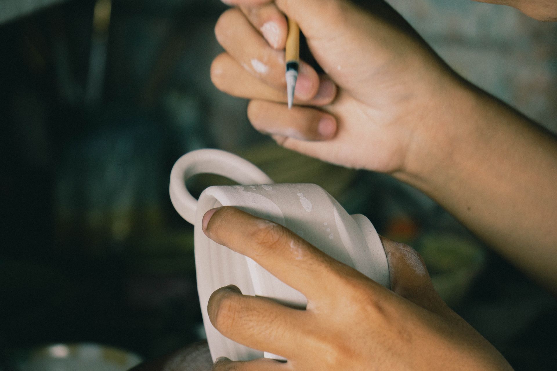 Artisan painting intricate designs on ceramic pottery in a close-up shot.