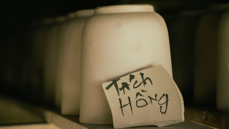 Row of unglazed ceramic pots in workshop with handwritten label.
