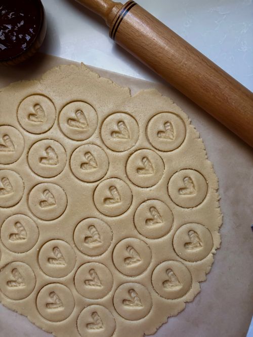 Free Heart-stamped cookie dough ready to bake with a rolling pin. Stock Photo