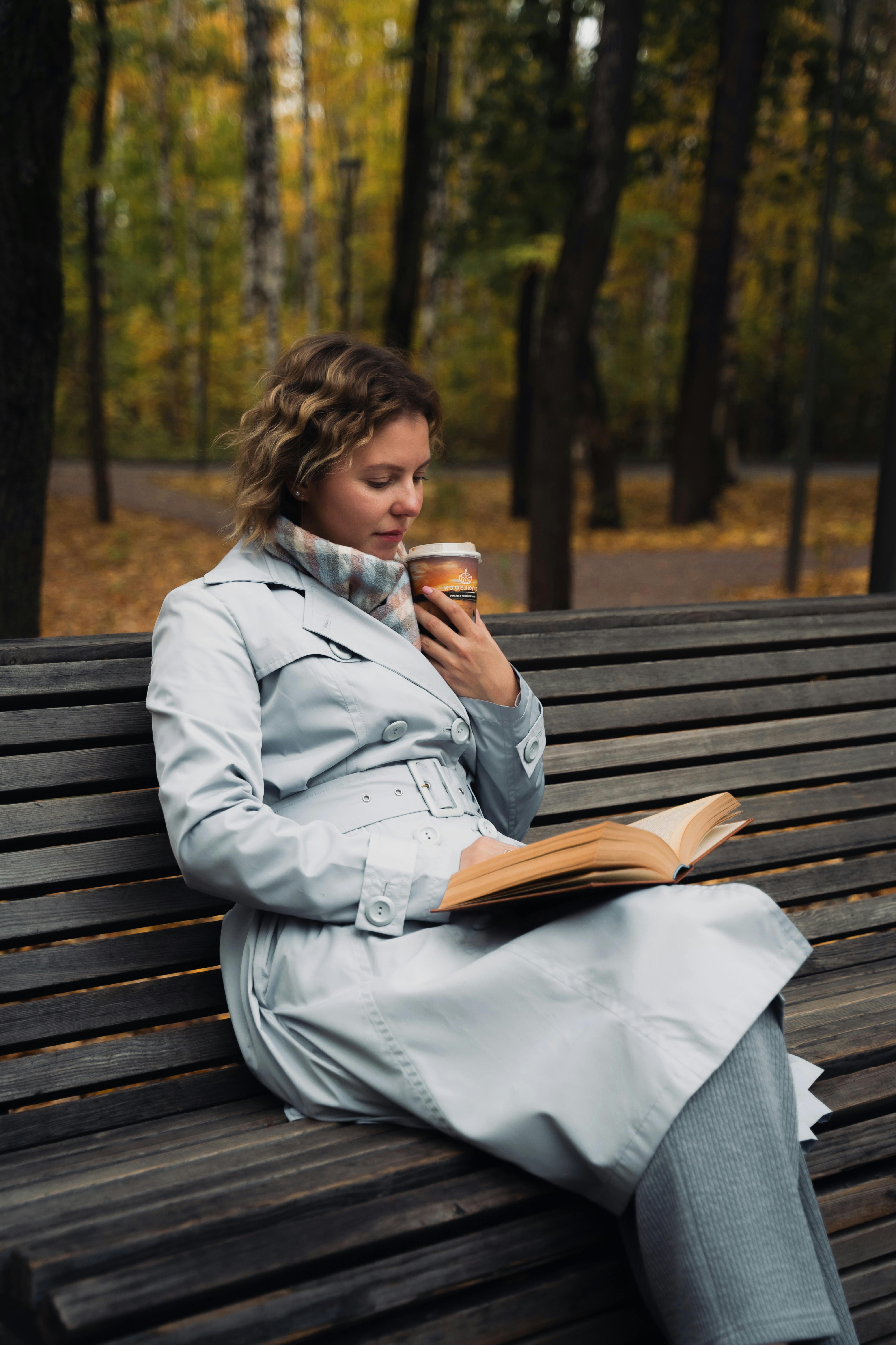 woman enjoying coffee and book in autumn park