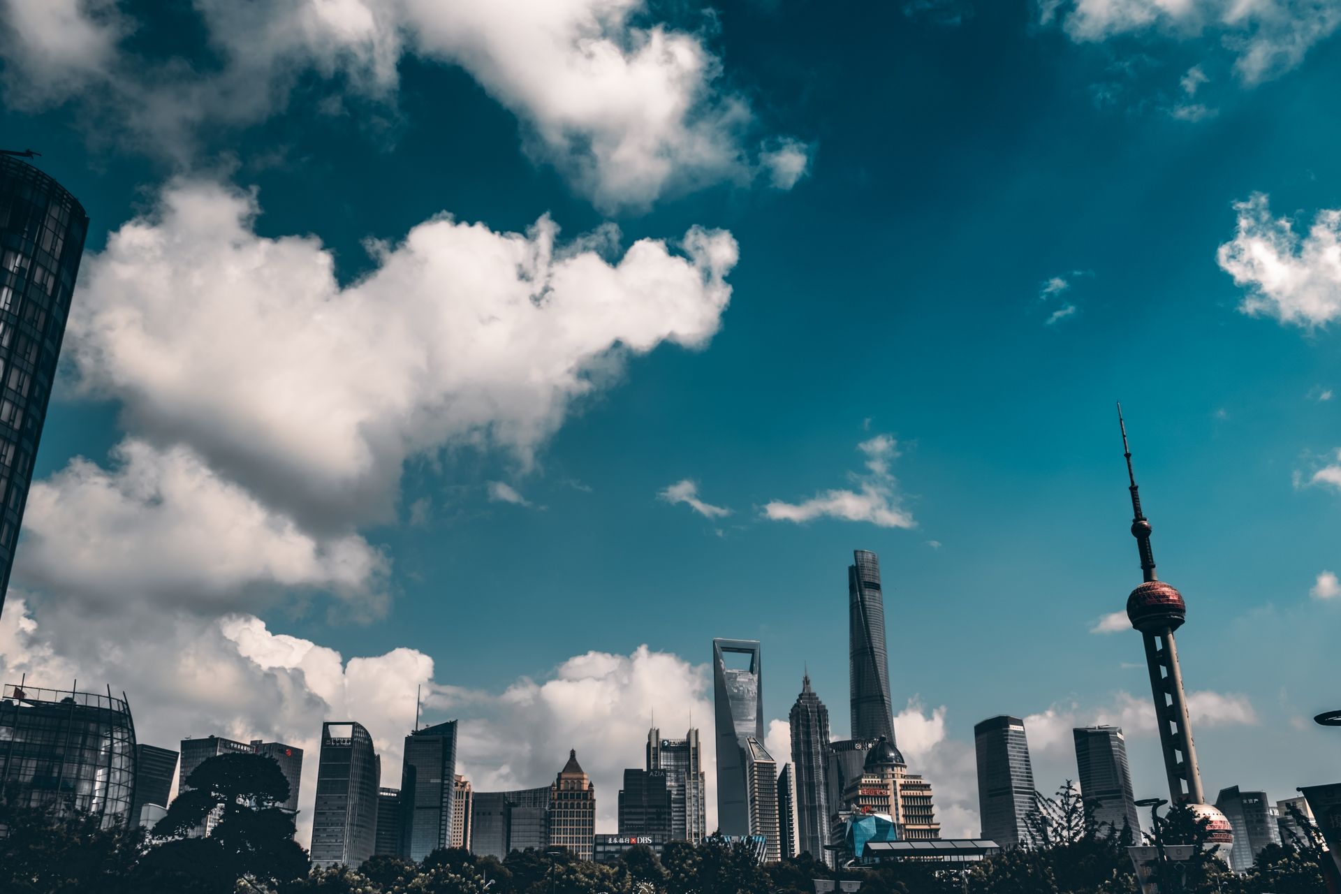 Panoramic view of Shanghai skyline showcasing iconic skyscrapers against a dramatic cloud-filled sky.