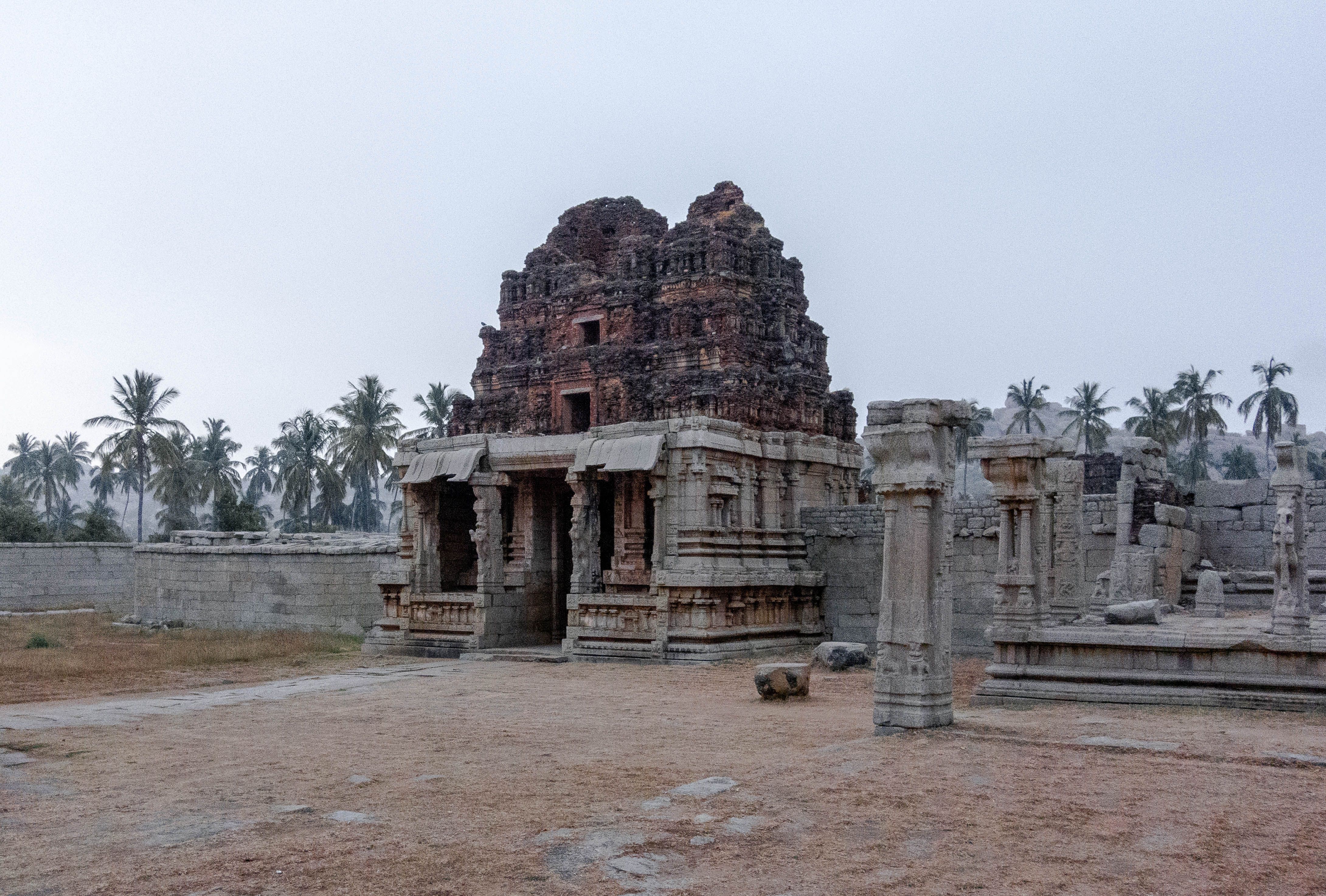 Explore the majestic ruins of an Indian temple surrounded by palms at dawn.