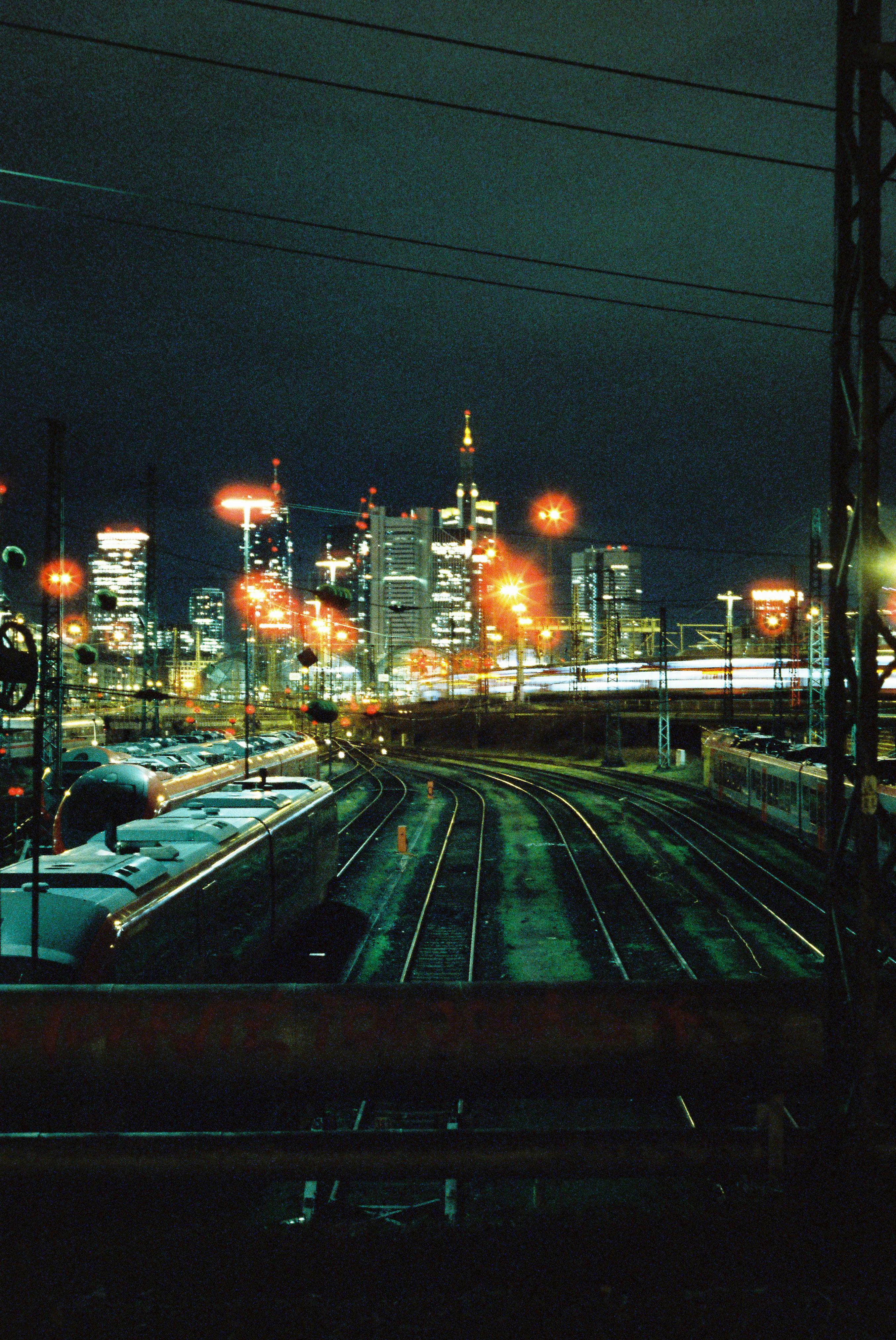 Urban night view with city lights, train tracks, and skyscrapers.
