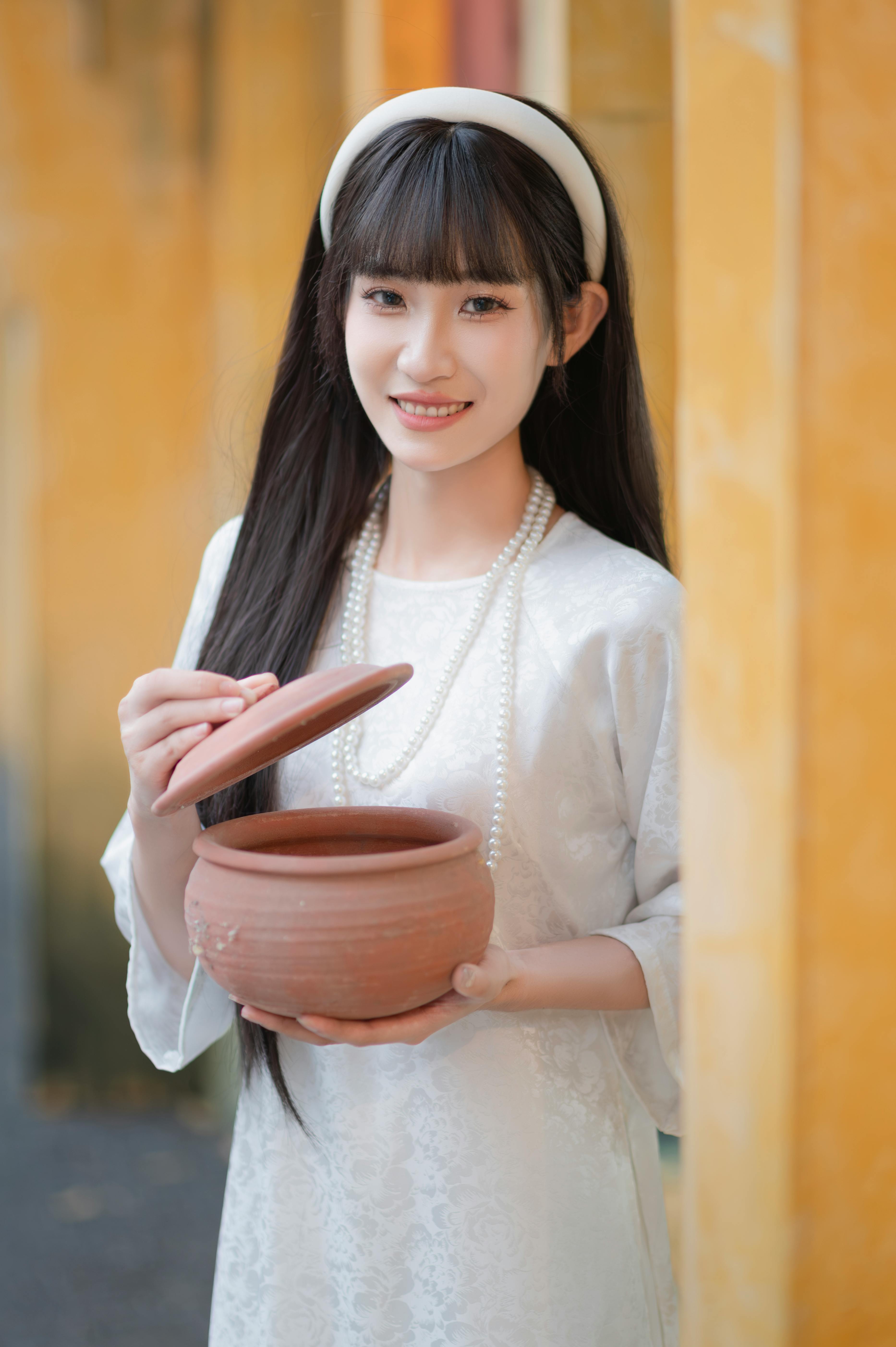 young woman holding clay pot outdoors