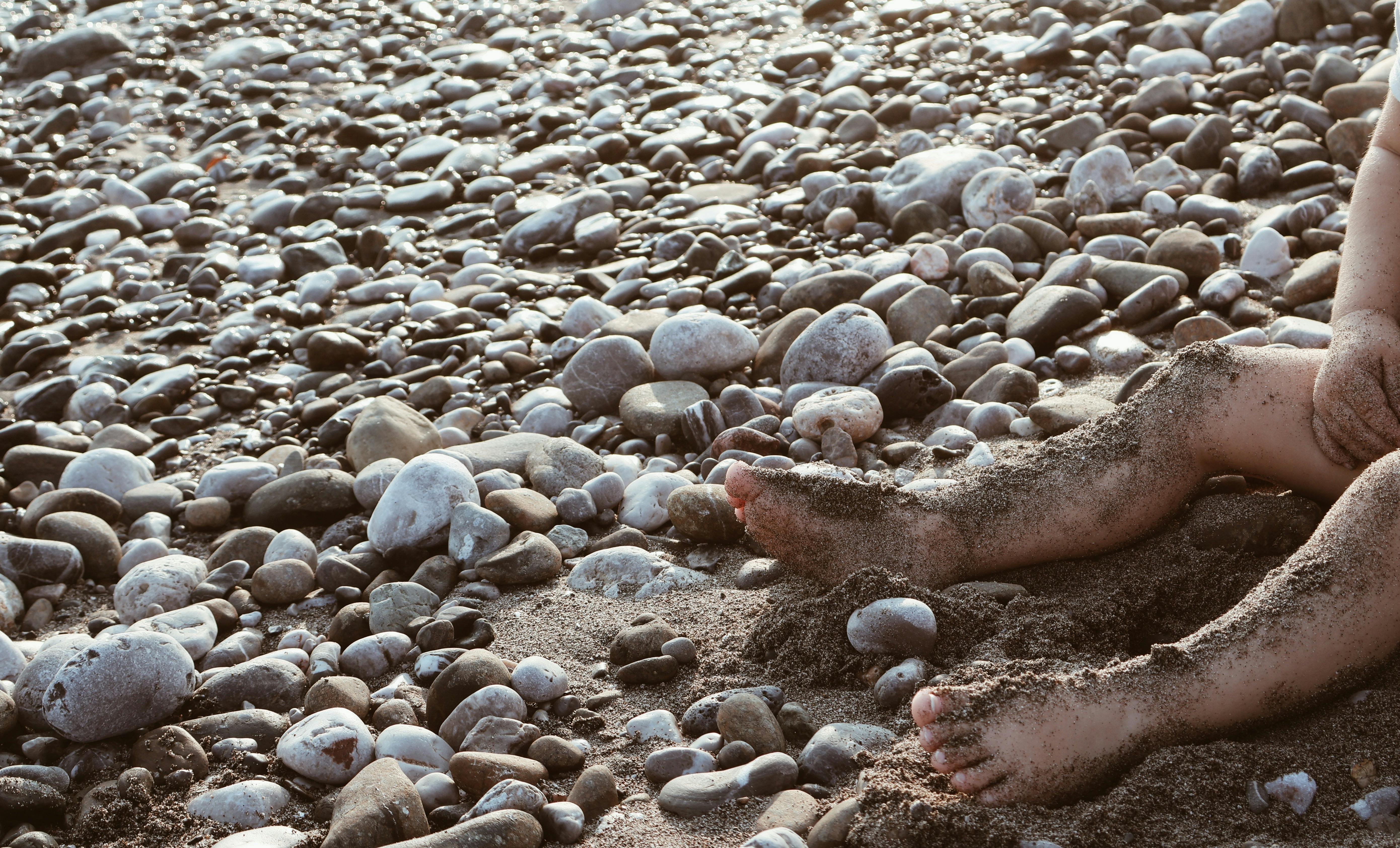 child s sandy feet on pebbled beach