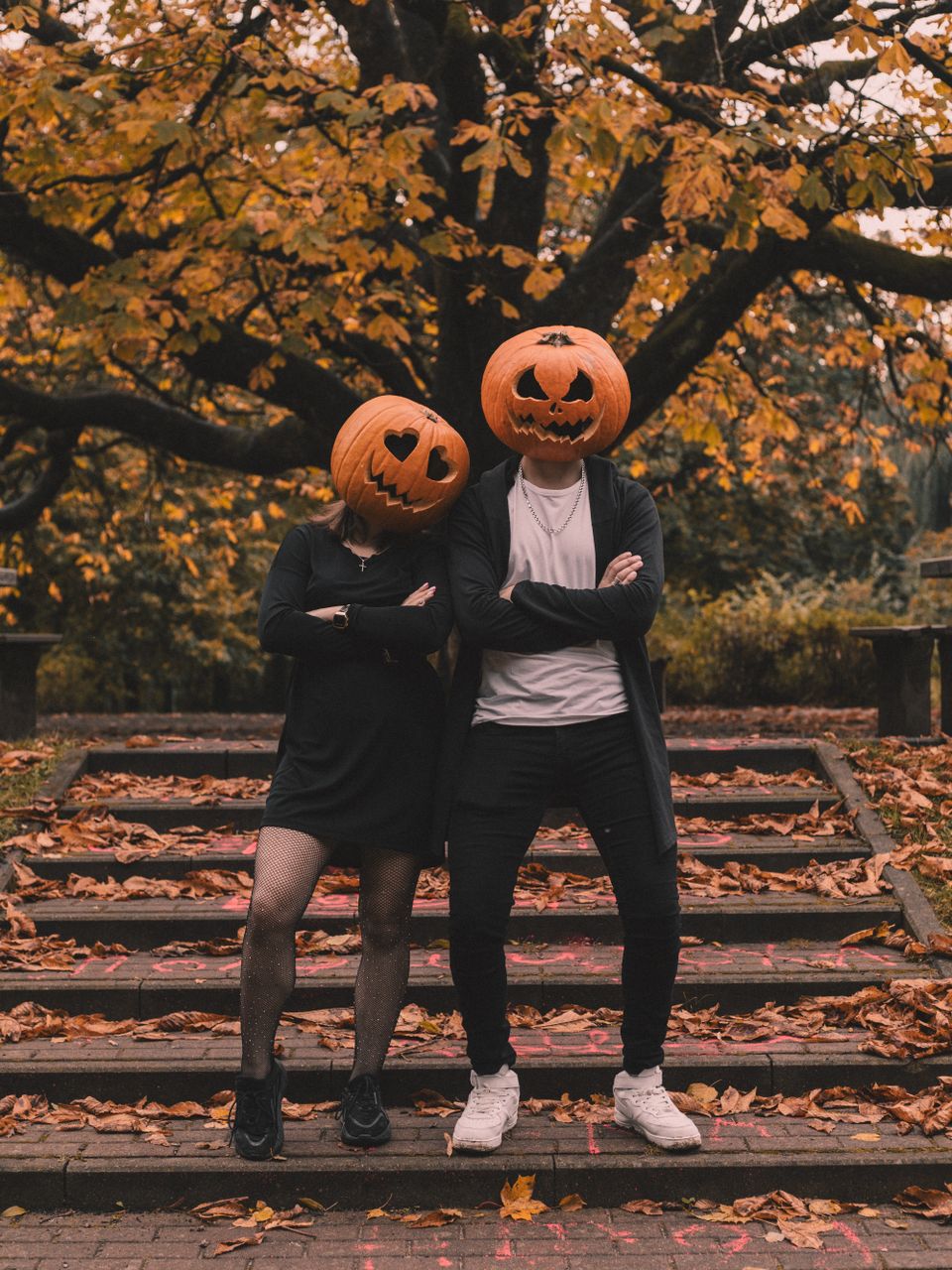 Adults in pumpkin-head costumes in an autumn scene