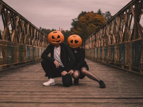 Free Couple in Halloween costumes with pumpkin heads on an old wooden bridge, adding a spooky charm to the scene. Stock Photo