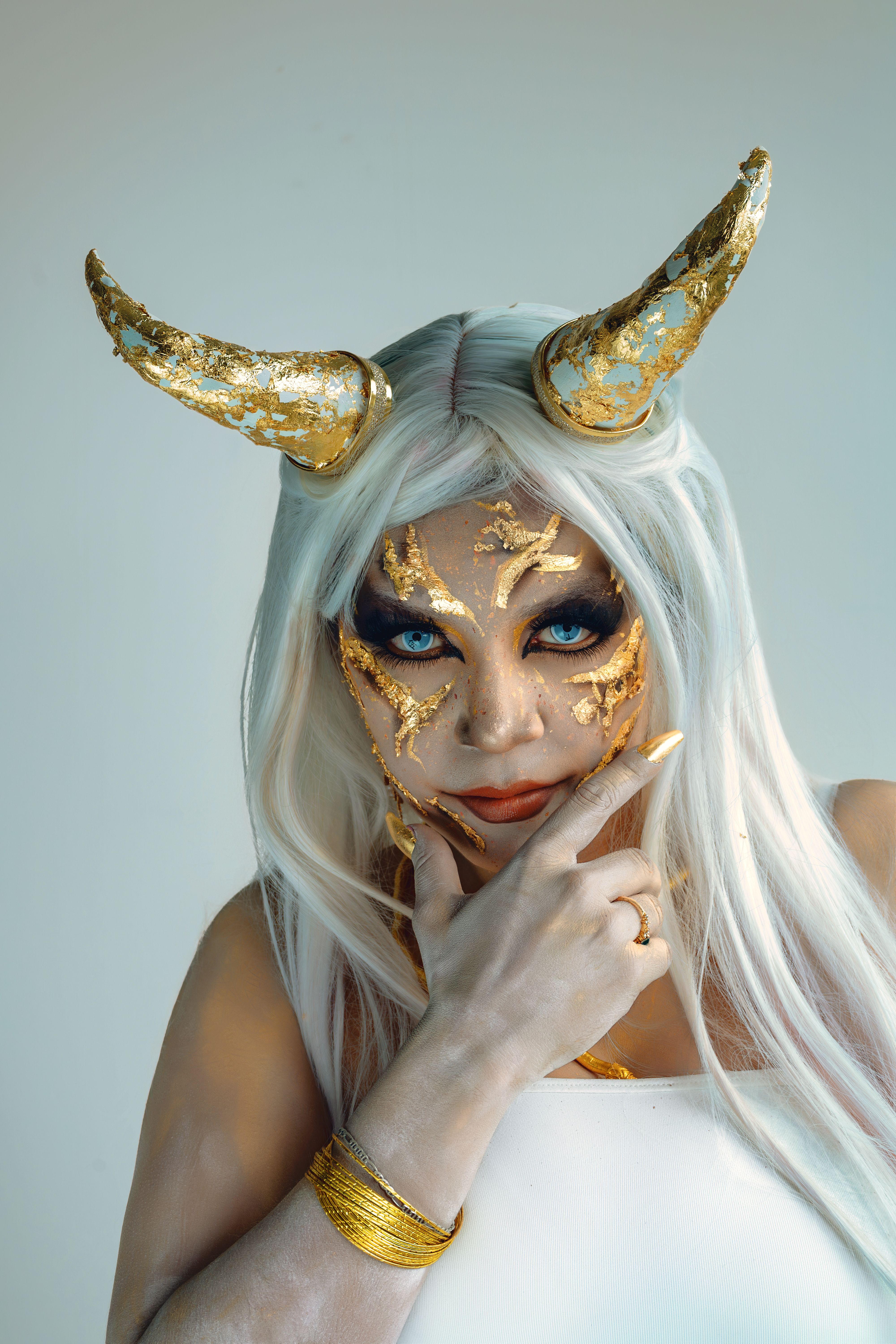 A striking fantasy-themed portrait of a woman with dramatic makeup and gold horns.