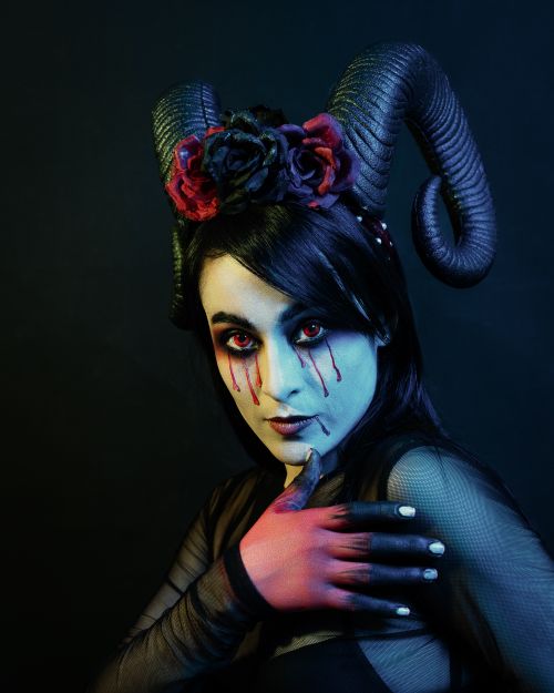 Free A woman adorned with horns and painted face, exuding mystique and fantasy allure. Stock Photo