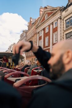 People exploring historic architecture on an open-top tour bus in a European city.