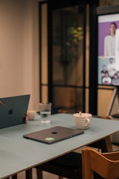 Modern office setup with laptops, coffee mugs, and a presentation screen, creating a relaxed work environment.