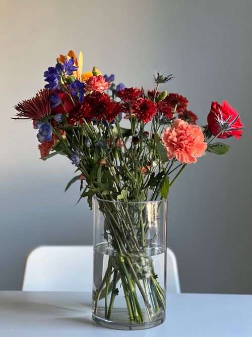 Free Colorful mixed flowers in a glass vase on a light background. Stock Photo