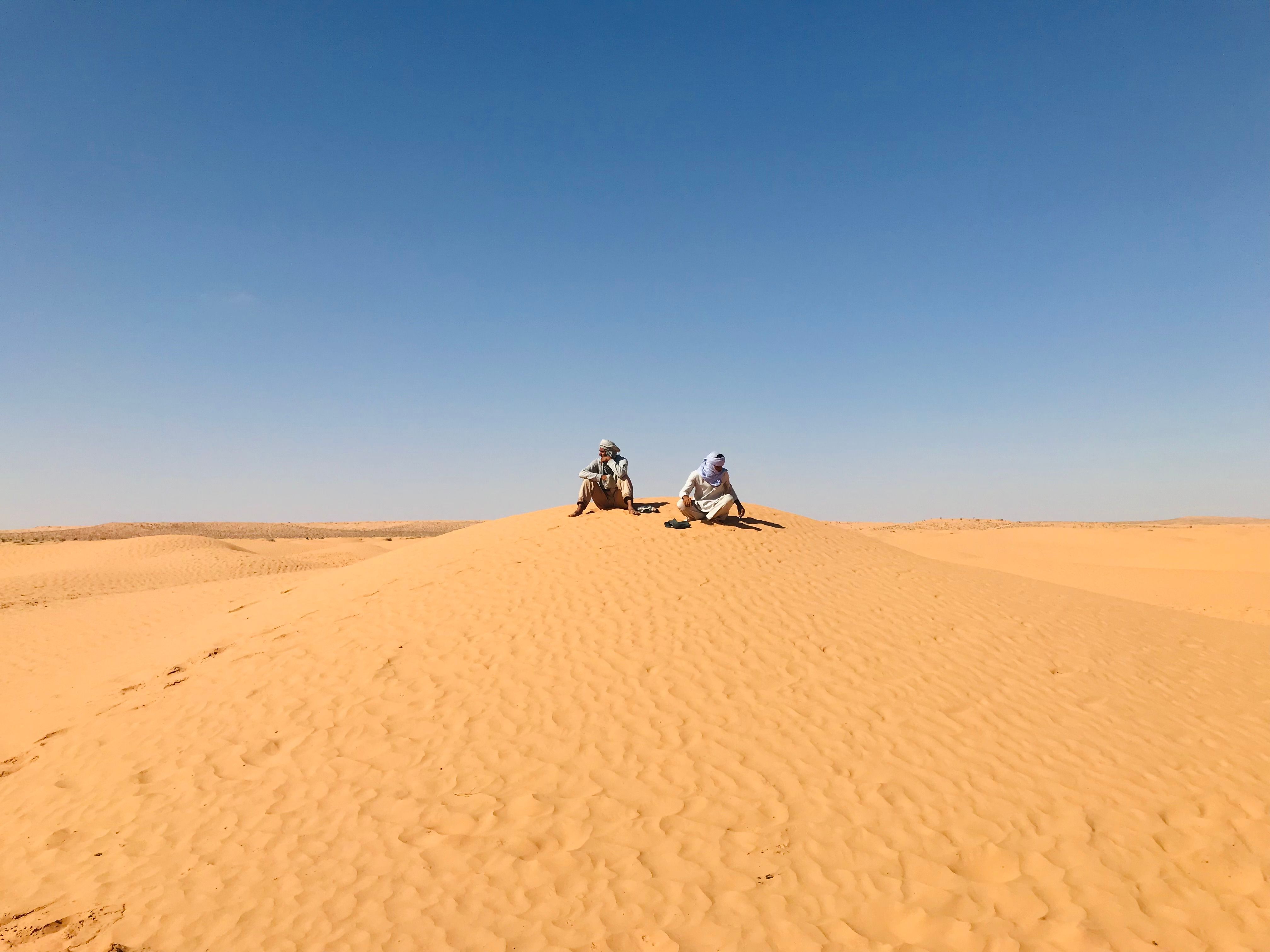 Two People Sitting on Desert Sand Dunes · Free Stock Photo