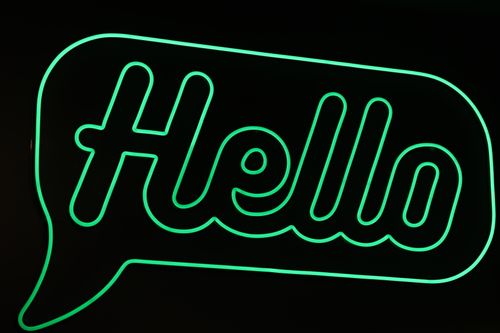 Free Bright green neon sign displaying 'Hello' in Catania, Sicily. Stock Photo