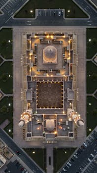 Stunning aerial night view of the illuminated Grand Mosque in Muscat, Oman, showcasing intricate architecture.