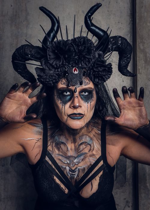 Free A person in an intricate Halloween costume with dark horror makeup, featuring horns and floral headpiece. Stock Photo