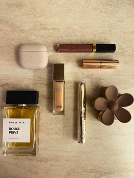 Flat lay of cosmetics and perfume on a neutral background.