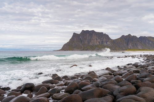 Free Serene rocky beach at Lofoten Islands, Norway, with waves crashing under a cloudy sky. Stock Photo