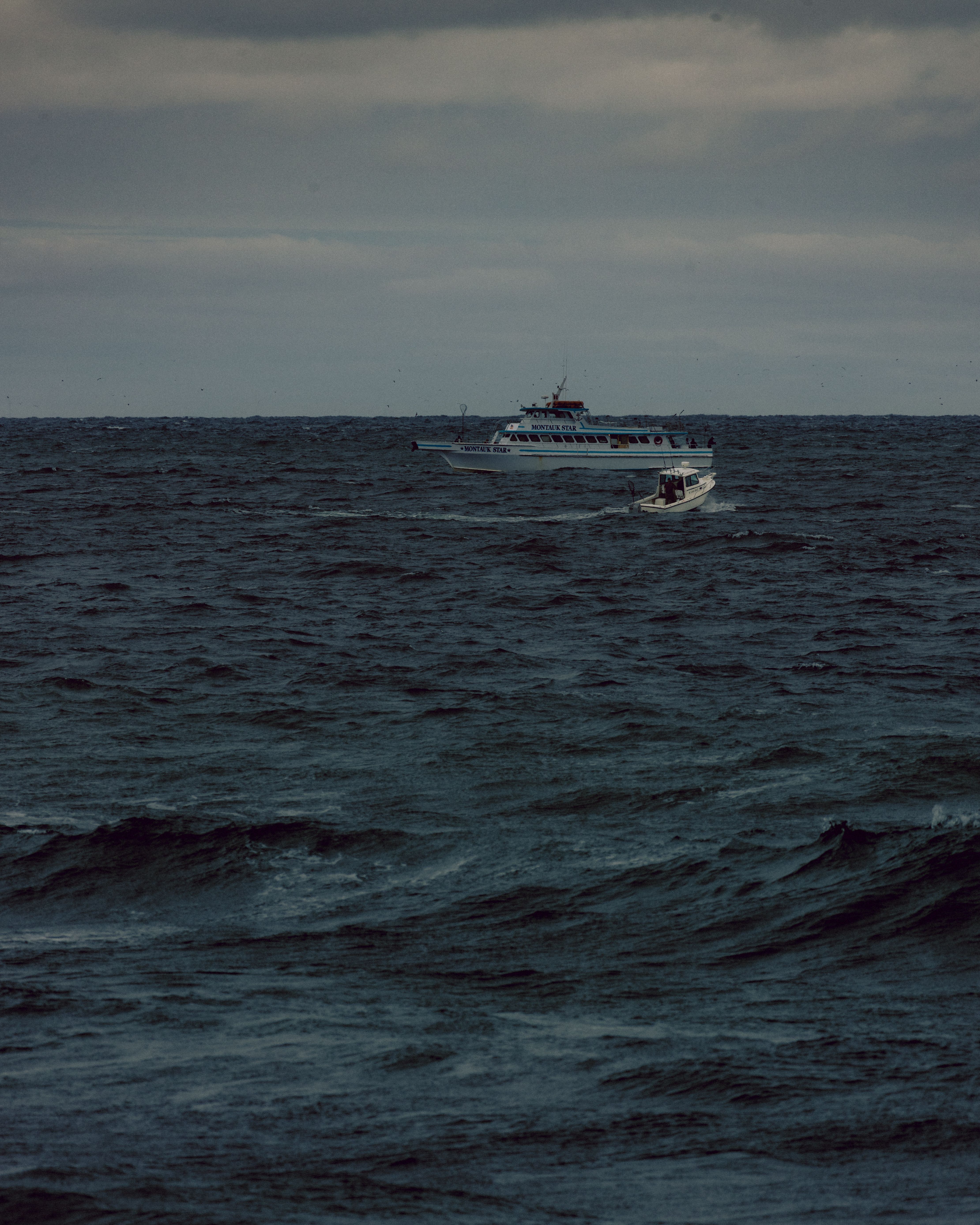 Dramatic Ocean Scene with Boats Under Cloudy Sky · Free Stock Photo