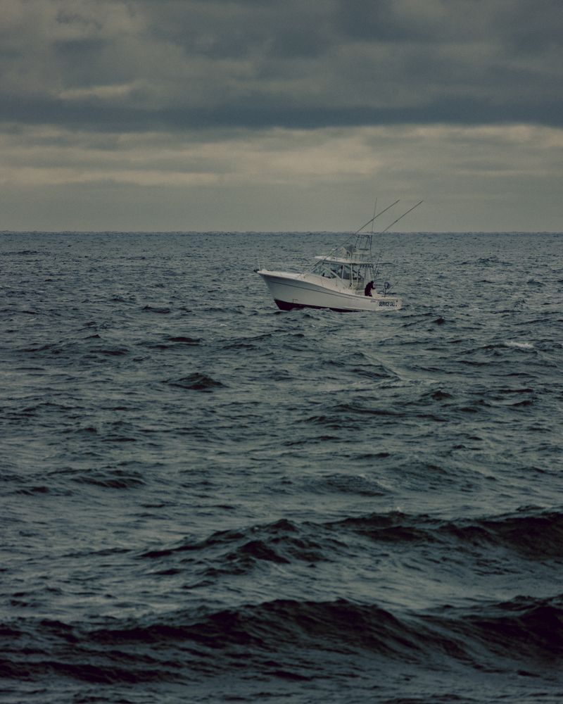 Lancha de pesca solitaria en mar abierto bajo cielo dramático