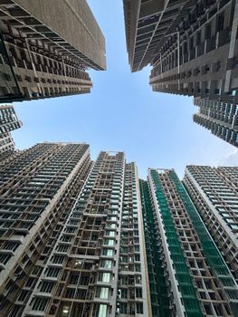 Dramatic upward view of dense urban skyscrapers with clear blue sky above.