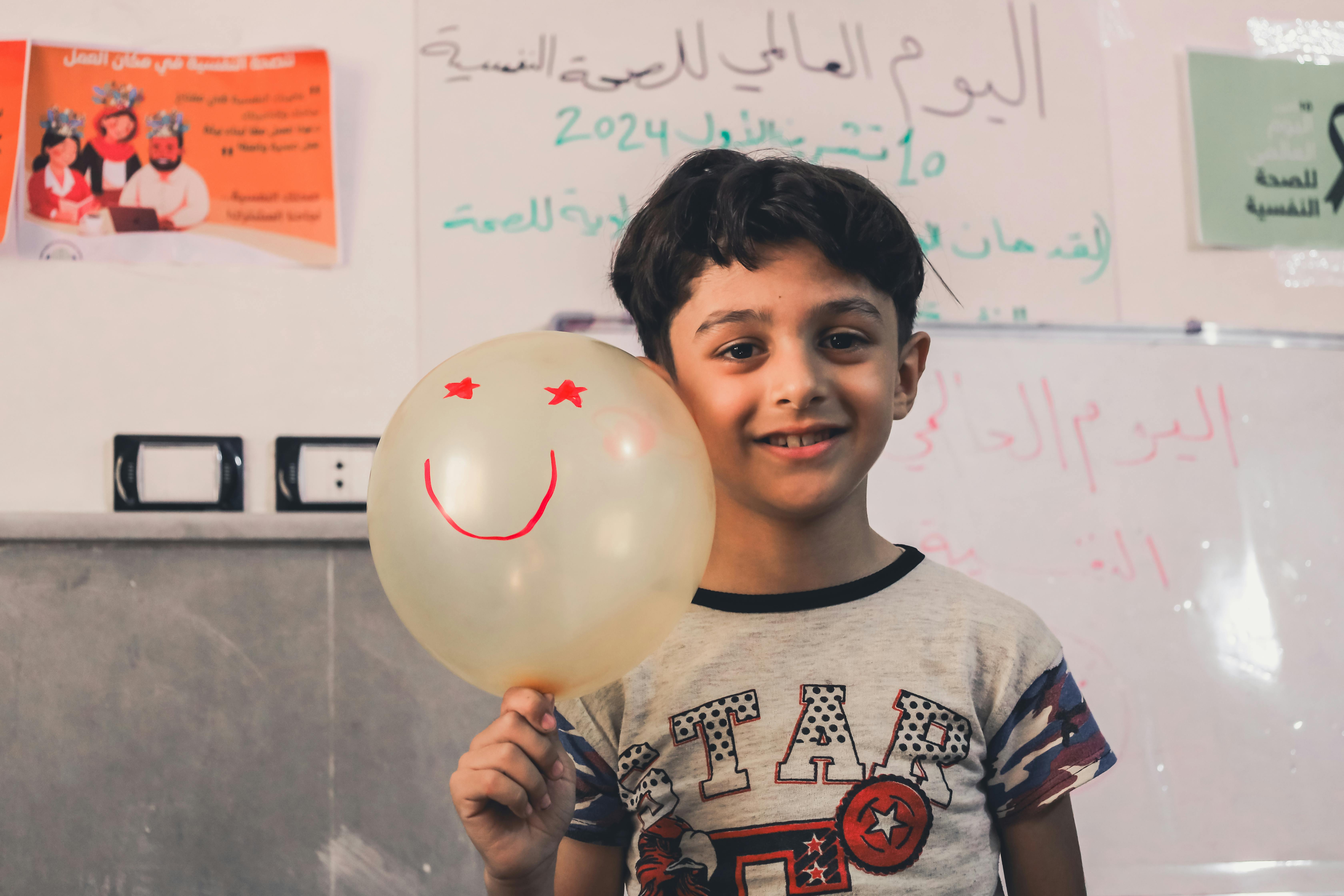 smiling child holding balloon in classroom