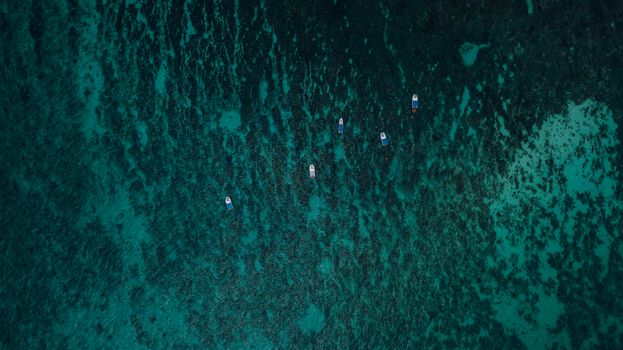 A stunning aerial view of boats floating over a vibrant, textured ocean surface, showcasing the beauty of sea patterns.