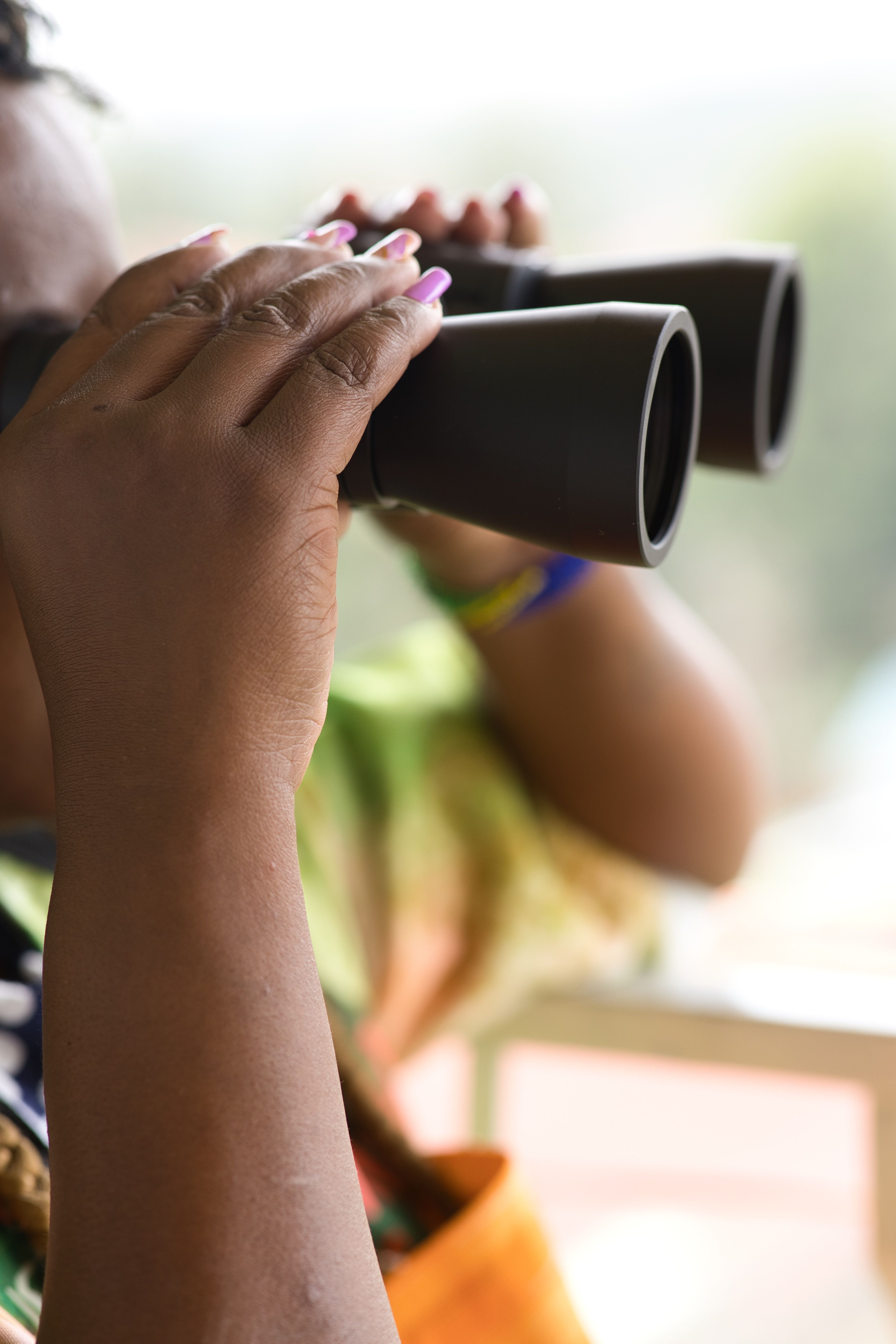 Close-up of hands holding binoculars, capturing outdoor scenery.